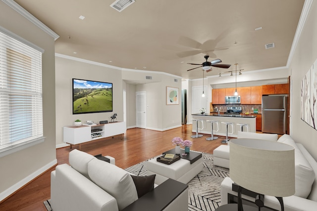 living room featuring ceiling fan, ornamental molding, and light hardwood / wood-style flooring