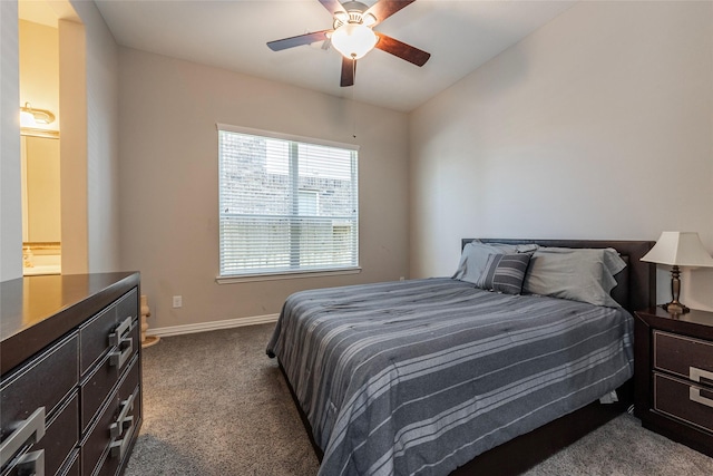 bedroom with dark colored carpet, ensuite bathroom, and ceiling fan