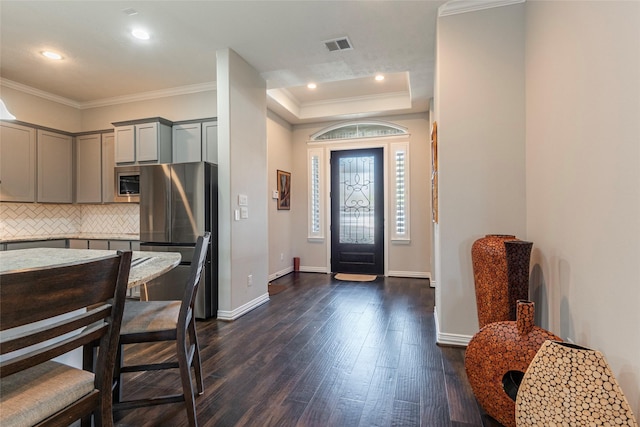 entrance foyer featuring dark wood-type flooring, ornamental molding, and a raised ceiling