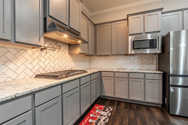 kitchen featuring crown molding, light stone counters, dark hardwood / wood-style floors, gray cabinets, and stainless steel appliances