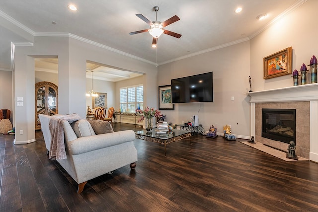 living room featuring hardwood / wood-style flooring, ceiling fan with notable chandelier, ornamental molding, and a tile fireplace