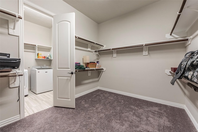 walk in closet with separate washer and dryer and carpet flooring