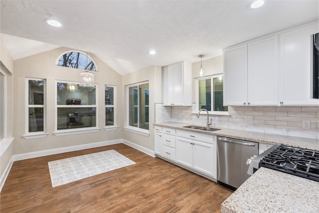 kitchen with pendant lighting, stainless steel appliances, vaulted ceiling, and white cabinets