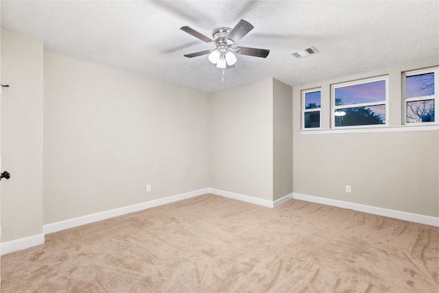 spare room with ceiling fan, light colored carpet, and a textured ceiling