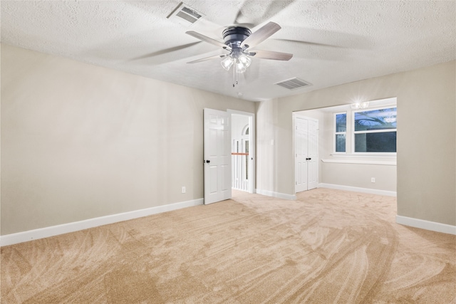 unfurnished room featuring ceiling fan, light carpet, and a textured ceiling