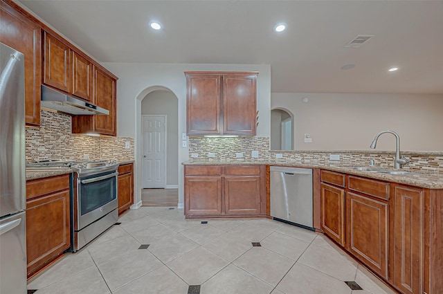 kitchen featuring sink, appliances with stainless steel finishes, backsplash, light stone countertops, and light tile patterned flooring