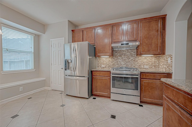 kitchen with stainless steel appliances, brown cabinets, decorative backsplash, and extractor fan