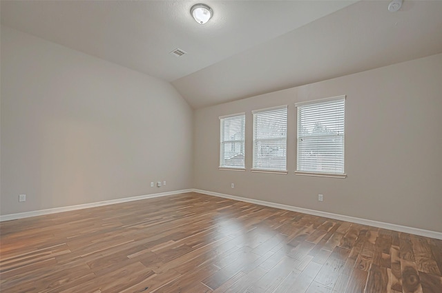 spare room with vaulted ceiling and wood-type flooring