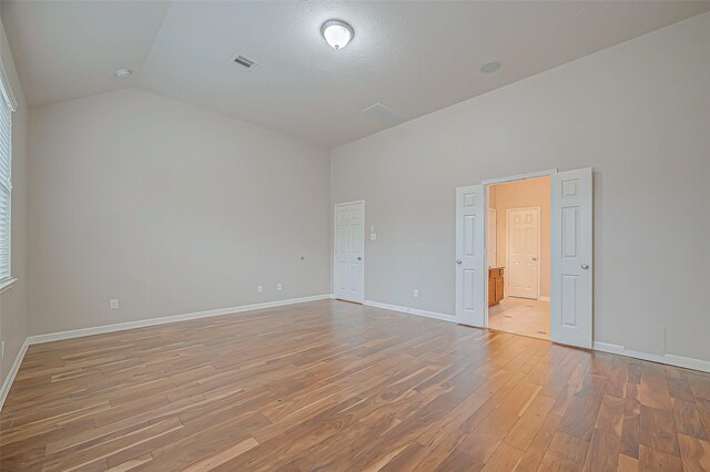 unfurnished room featuring lofted ceiling and hardwood / wood-style floors