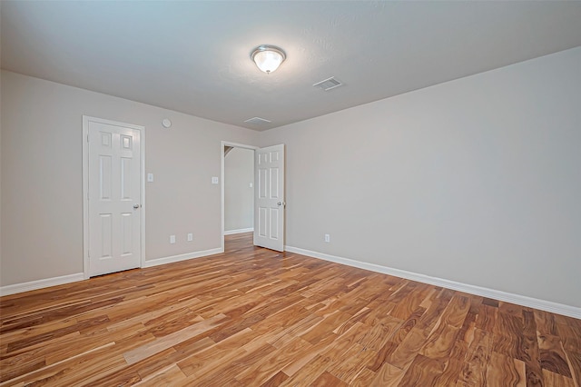 unfurnished room with light wood-style flooring, visible vents, and baseboards