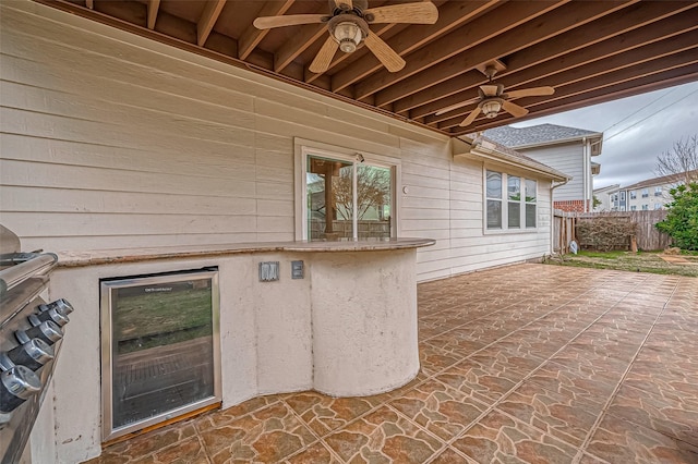 view of patio / terrace featuring wine cooler, fence, and a ceiling fan