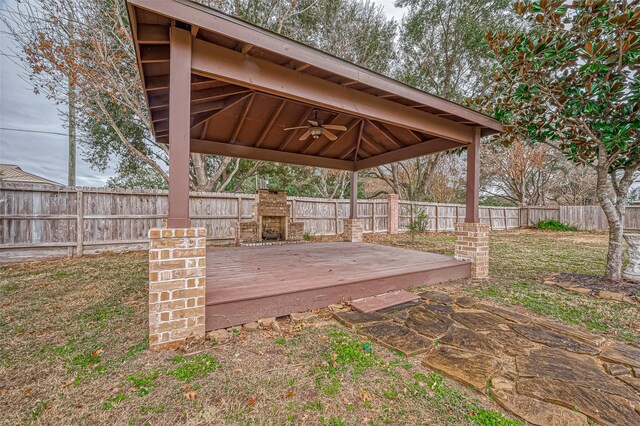 wooden terrace with exterior fireplace, a gazebo, and ceiling fan