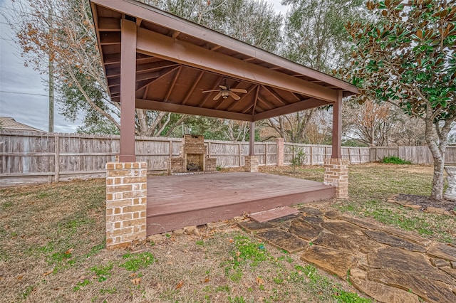 deck featuring a fenced backyard, ceiling fan, exterior fireplace, and a gazebo