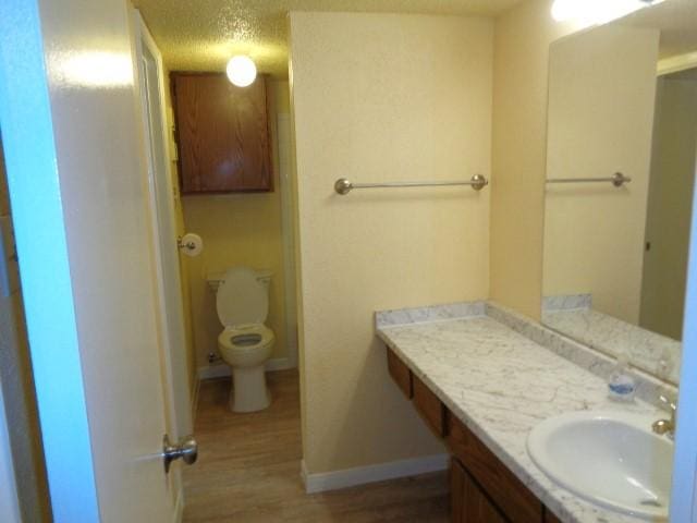 bathroom featuring vanity, hardwood / wood-style flooring, a textured ceiling, and toilet