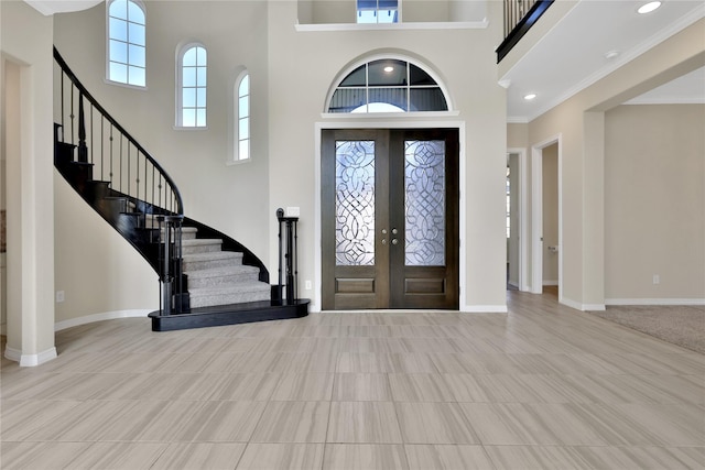 entryway with french doors, a towering ceiling, and ornamental molding