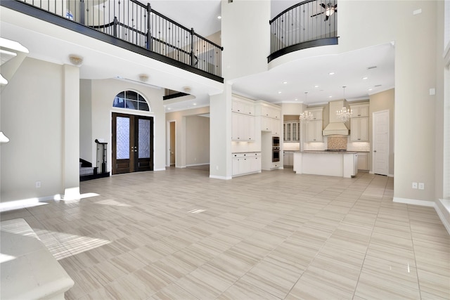 unfurnished living room with french doors, light tile patterned floors, and a high ceiling