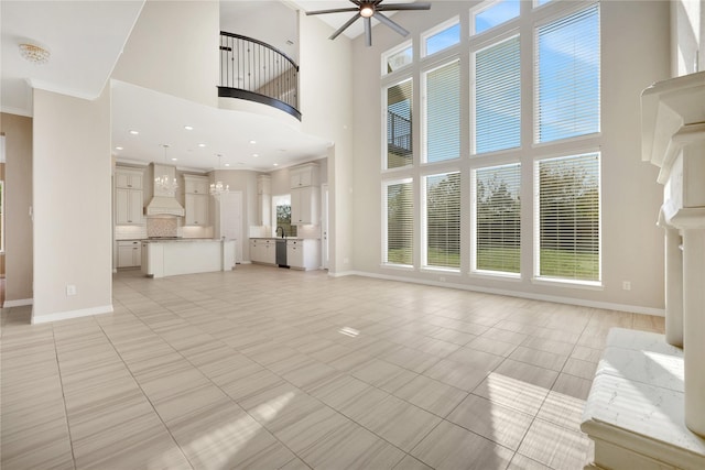 unfurnished living room with light tile patterned flooring, ceiling fan, and a high ceiling