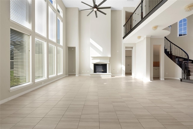 unfurnished living room with a high ceiling, light tile patterned floors, and ceiling fan