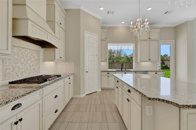 kitchen featuring hanging light fixtures, light stone countertops, a center island, and stainless steel gas cooktop