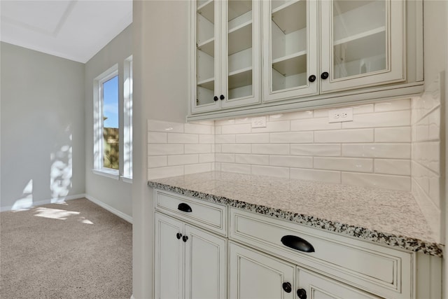 kitchen with a healthy amount of sunlight, carpet flooring, light stone countertops, and decorative backsplash