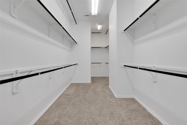 walk in closet with light colored carpet