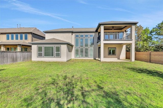 rear view of house featuring ceiling fan, a balcony, a yard, and a patio