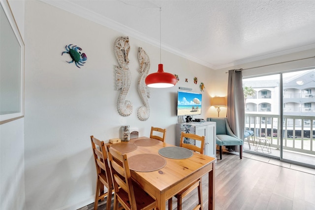 dining room featuring ornamental molding, light hardwood / wood-style floors, and a textured ceiling