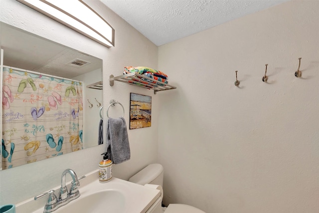 bathroom with vanity, toilet, and a textured ceiling