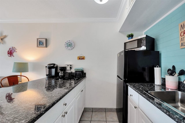 kitchen with sink, white cabinets, ornamental molding, light tile patterned floors, and stainless steel appliances