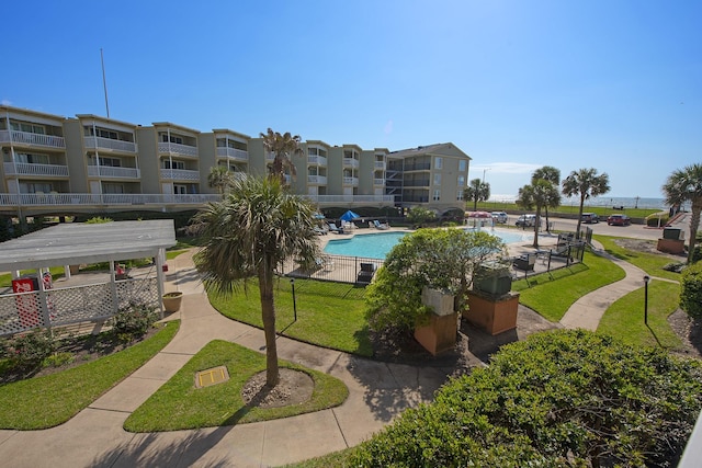 view of home's community with a pool and a yard