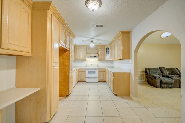 kitchen featuring light brown cabinets, a textured ceiling, light tile patterned floors, and electric stove