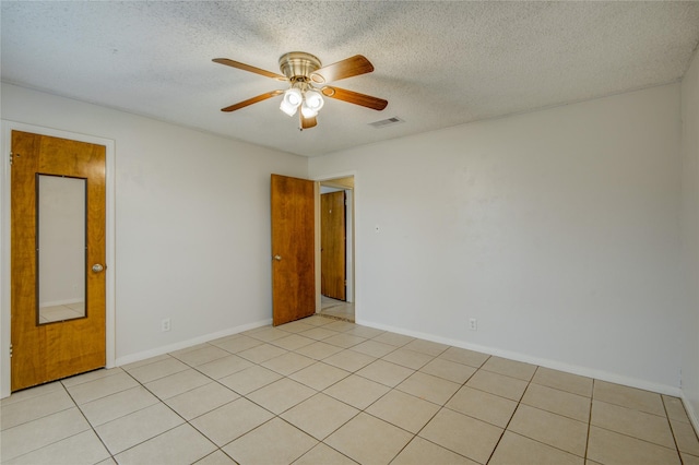 tiled spare room with a textured ceiling and ceiling fan