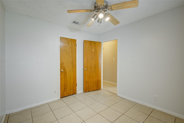 tiled spare room with ceiling fan and a textured ceiling