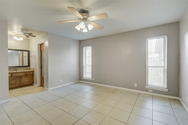 tiled empty room with ceiling fan, a textured ceiling, and a healthy amount of sunlight