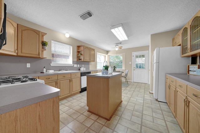 kitchen featuring stove, dishwashing machine, a kitchen island, and light brown cabinets