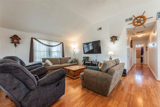 living room with visible vents, vaulted ceiling, and light wood finished floors