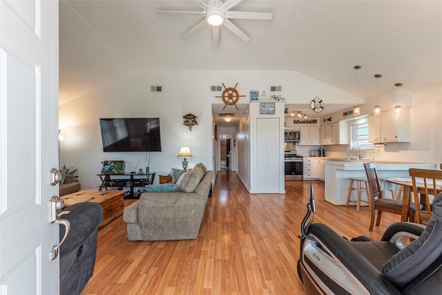 living room with visible vents, vaulted ceiling, and light wood finished floors