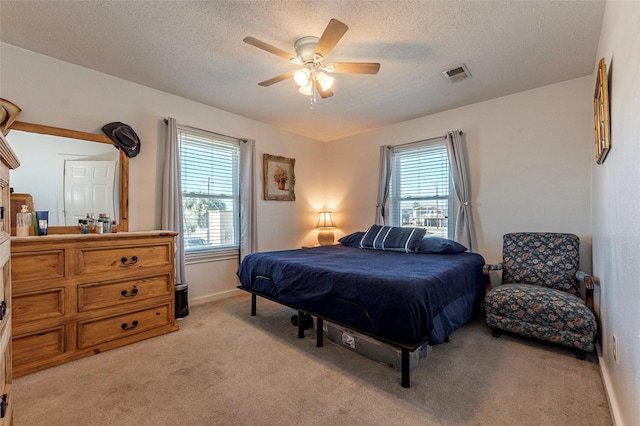 bedroom with light carpet, multiple windows, visible vents, and a textured ceiling