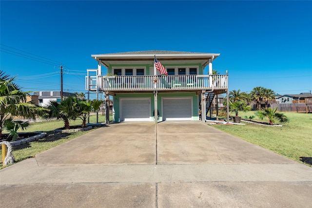 beach home featuring a balcony, a garage, and a front yard