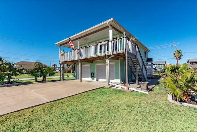 back of property with driveway, stairway, an attached garage, and a lawn