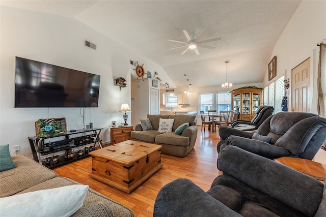 living room featuring light wood-style flooring, visible vents, vaulted ceiling, and ceiling fan with notable chandelier