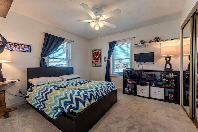 carpeted bedroom with ceiling fan, baseboards, and a textured ceiling