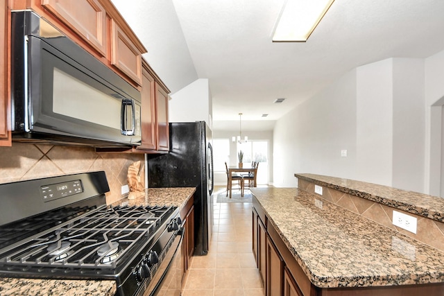 kitchen with tasteful backsplash, stone countertops, a chandelier, light tile patterned floors, and gas range oven