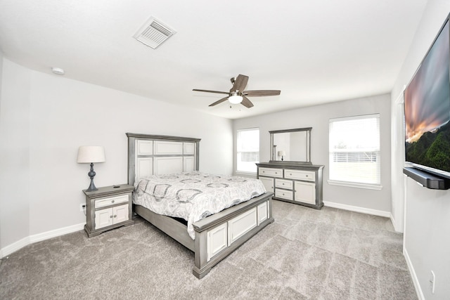 bedroom featuring ceiling fan, light colored carpet, and multiple windows