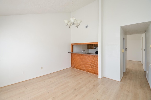 interior space featuring high vaulted ceiling, light hardwood / wood-style floors, and a chandelier