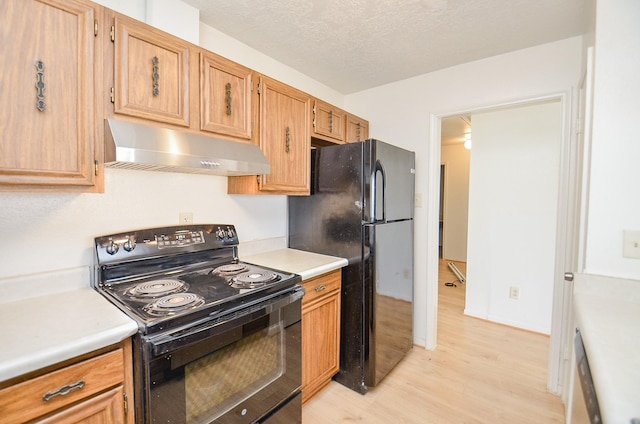 kitchen featuring light wood-type flooring, a textured ceiling, and black appliances