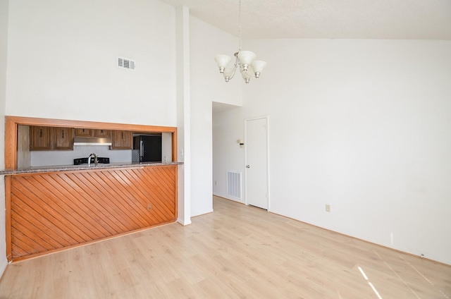 interior space with sink, a notable chandelier, light hardwood / wood-style floors, and high vaulted ceiling