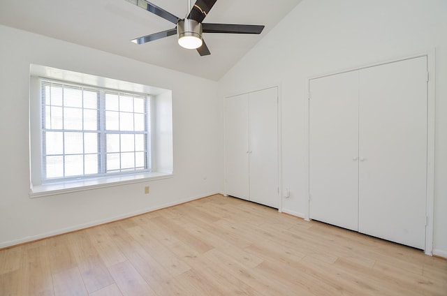 unfurnished bedroom featuring multiple closets, lofted ceiling, light wood-type flooring, and ceiling fan