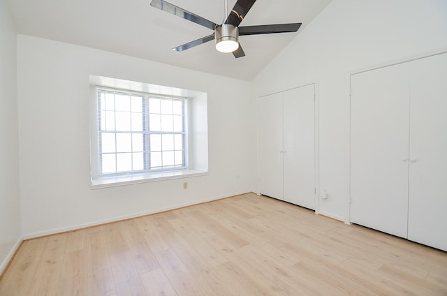 unfurnished bedroom featuring two closets, light hardwood / wood-style flooring, ceiling fan, and vaulted ceiling