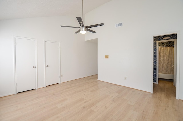 unfurnished bedroom featuring multiple closets, ceiling fan, high vaulted ceiling, and light hardwood / wood-style floors